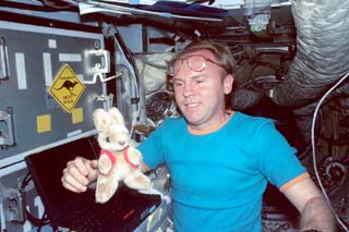 Mir-25 crewmember Andrew Thomas poses with personal Flight Data File (FDF) items in the Mir Space Station including stuffed animals and a patch. 